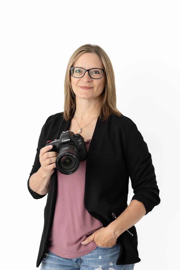 Woman holding a Canon camera, smiling.