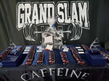 Trophies and medals displayed for a powerlifting event called Grand Slam.