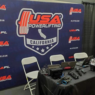 USA Powerlifting California event setup with microphones and laptops.