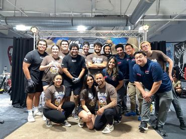 Group photo of diverse people at a USA Powerlifting event indoors.