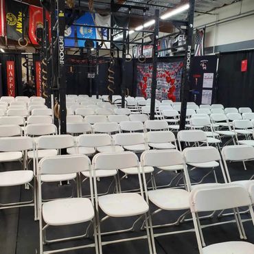 Rows of white folding chairs set up in a gym with Valentine decorations.
