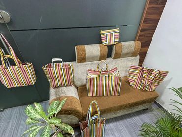 Multiple striped bags arranged on a sofa and floor next to plants.