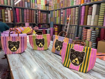 Colorful striped bags with leopard faces in a vibrant fabric store.