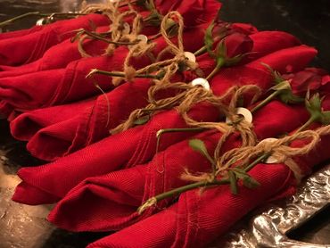 Red napkins tied with string and roses on a decorative tray.
