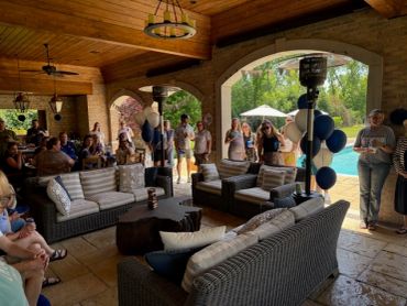 People gathered under a covered patio near a pool.