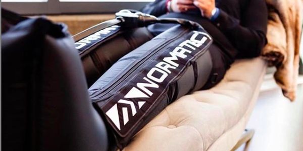 Person using NormaTec compression boots on their legs.