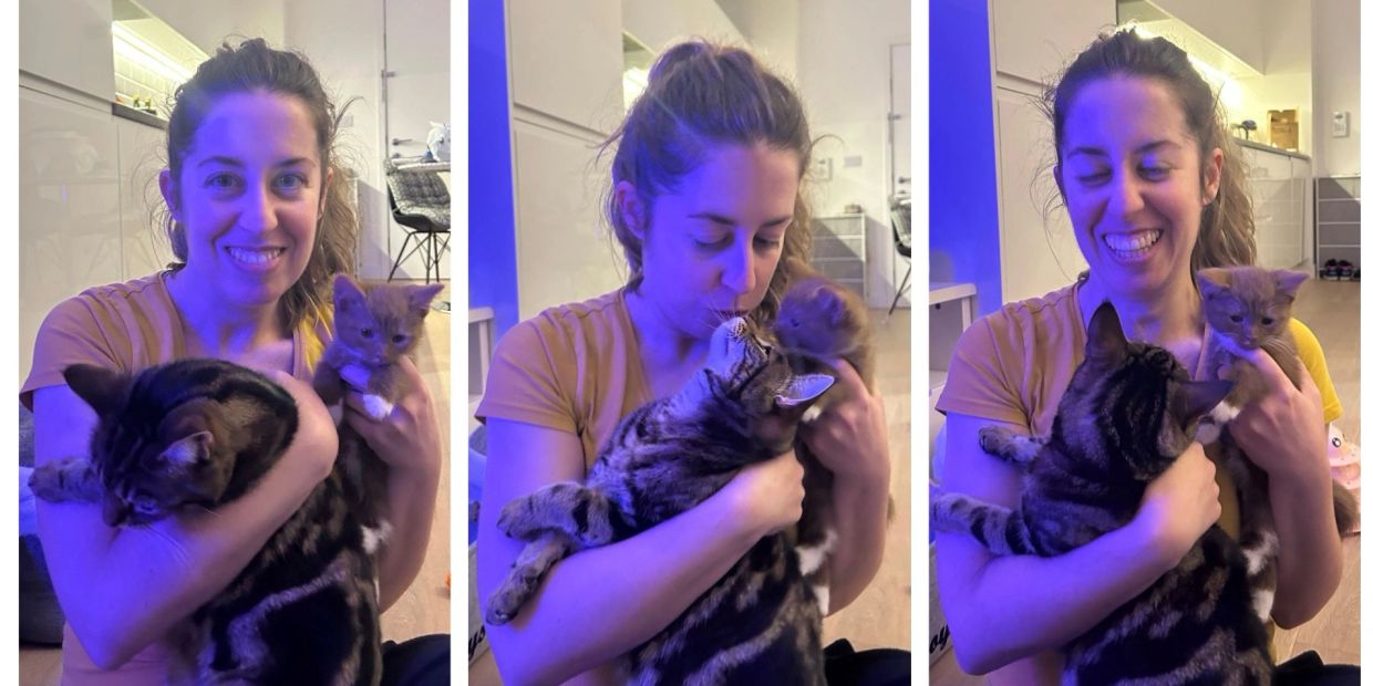Woman holding a cat and kitten, sharing affectionate moments.