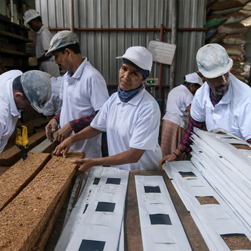 Workers in white uniforms processing and packaging blocks of materials in a factory.