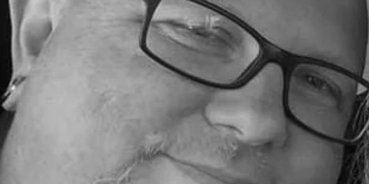 Close-up of a man wearing glasses with a slight smile.