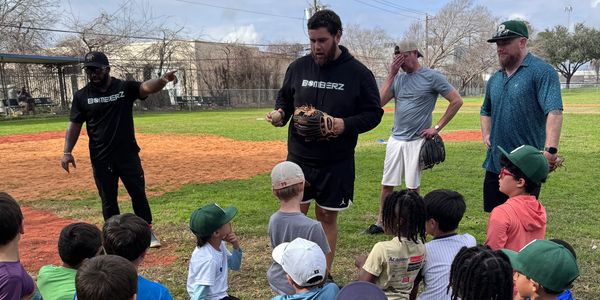 Coaches instruct young baseball players on the field during practice.