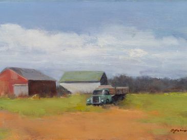 A vintage truck parked near two barns in a rural landscape.