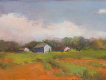 A peaceful rural landscape with barns under a cloudy sky.
