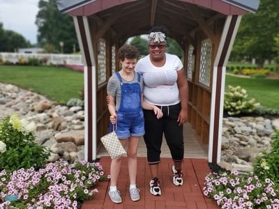 A Supporting Independence friend and employee enjoy an outdoor park, flowers and greenery.