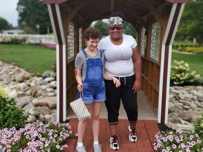 A Supporting Independence friend and employee enjoy an outdoor park, flowers and greenery.