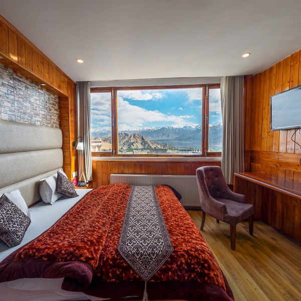 Cozy wooden-paneled hotel room with mountain view through large window.