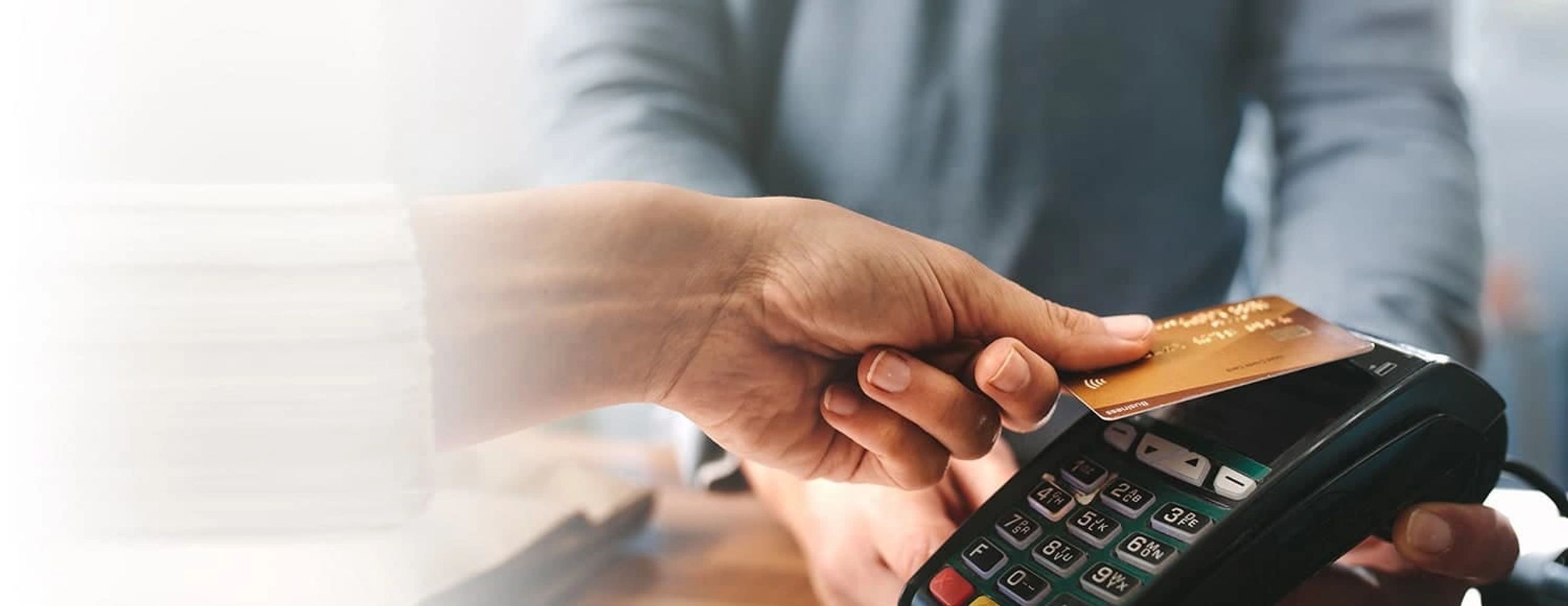 Person making a contactless payment with a credit card at a terminal.