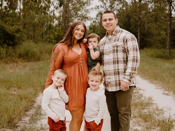 A happy family of five posing on a forest path.