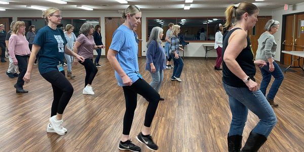 Group of women practicing line dancing in a studio.