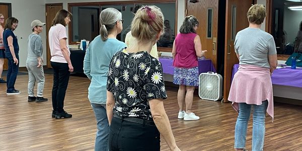Group of women standing in a room, seemingly preparing for an activity.