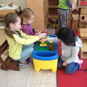 Three preschool students playing with building blocks.