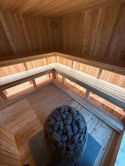 Cozy wooden sauna interior with heated stones in the center.