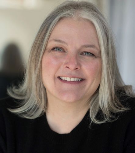Smiling middle-aged woman with gray hair and blue eyes wearing a black sweater. Health. Therapy for Men