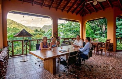 Four people having a meeting on a tropical veranda.