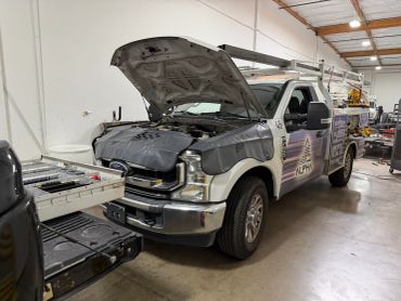 Work truck with open hood in a garage.