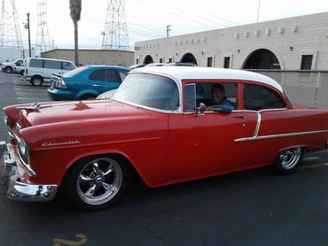 Classic red and white Chevrolet car with a smiling driver.