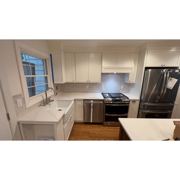 Modern kitchen with white cabinets, stainless steel appliances, and wooden flooring.