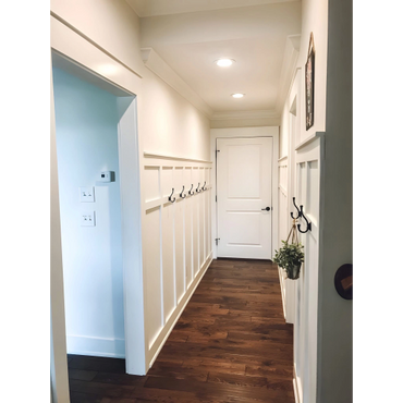 Bright hallway with white paneled walls and dark wooden floor.