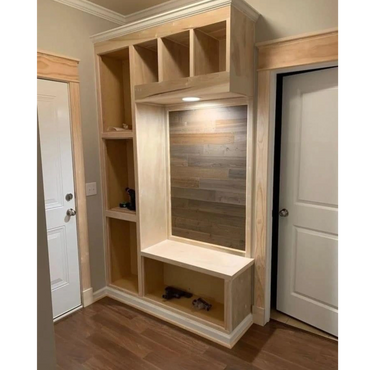 Unfinished wooden storage unit with cubbies and a bench, set against a wall with two doors.