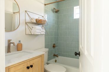 Bright bathroom with teal tiles and wooden vanity.