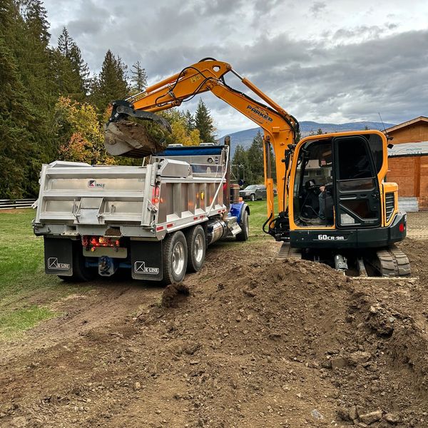 Excavator loading dirt into a dump truck at a construction site.