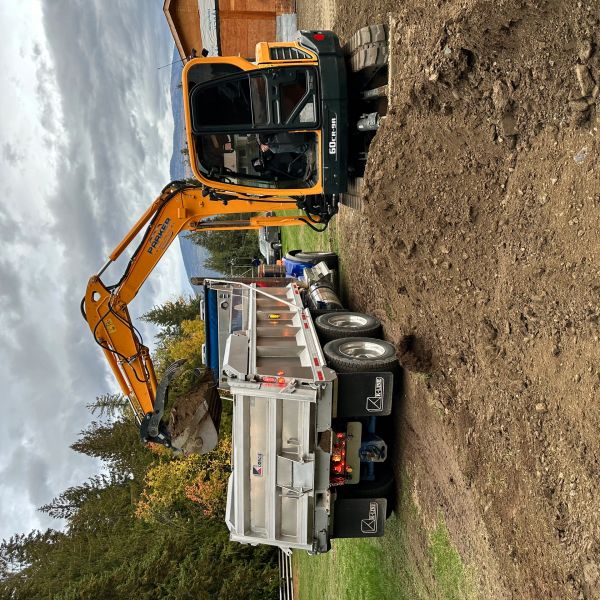 Excavator loading dirt into a dump truck at a construction site.