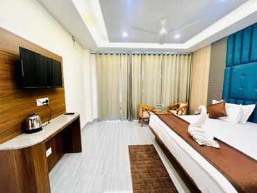 Modern hotel room with a large bed, TV, and seating area.