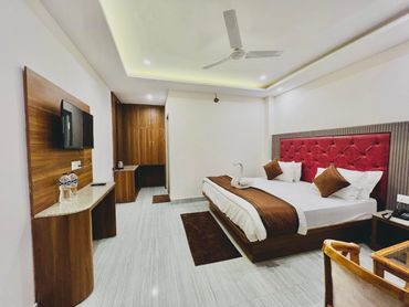 Modern hotel room with a red tufted headboard and wooden furniture.