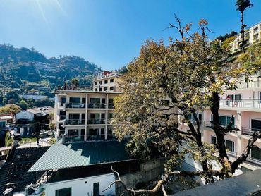 Sunny day with buildings and trees in a mountainous area.