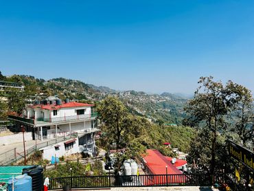Mountain town with red-roofed buildings and lush green trees under a clear blue sky.