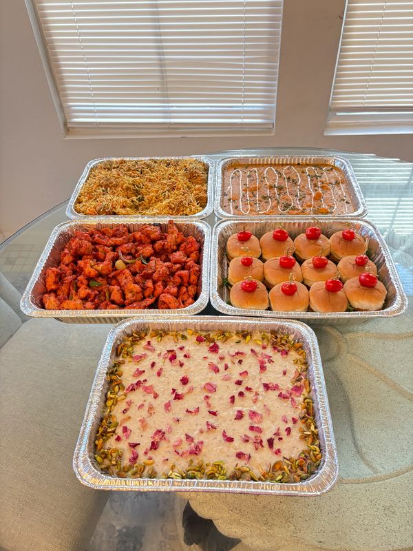 A variety of Indian dishes served in foil trays on a glass table.