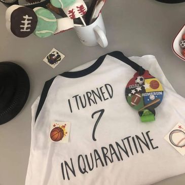 A shirt reading 'I turned 7 in quarantine' surrounded by sports-themed items.