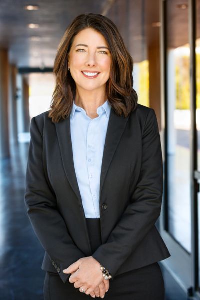 Confident woman in business attire standing in a modern office hallway.