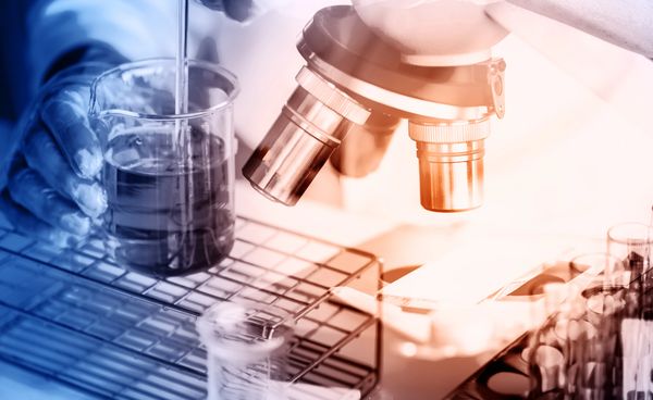 Scientist using a microscope and pipette in a laboratory setting.
