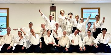Group photo of martial artists in white uniforms posing indoors.