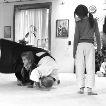 People practicing martial arts indoors, one person in a headstand pose.