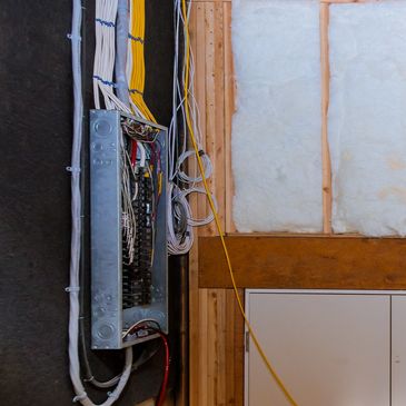 Open panel with neat wiring on an unfinished wall - showcasing rewire services