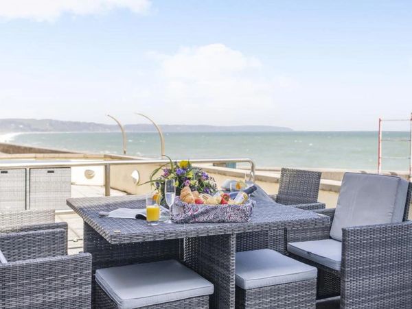 Outdoor dining setup with wicker furniture overlooking the ocean.