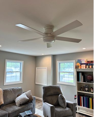 Modern living room with gray furniture and a white ceiling fan.