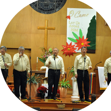 A group of men singing in a church with Christmas decorations.