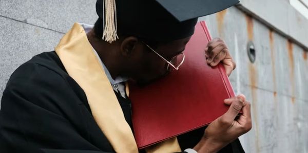 Graduate kissing diploma with joy and pride.